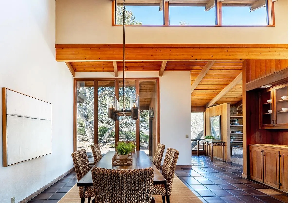 The dining table under the wood beams, oaks at the glass
